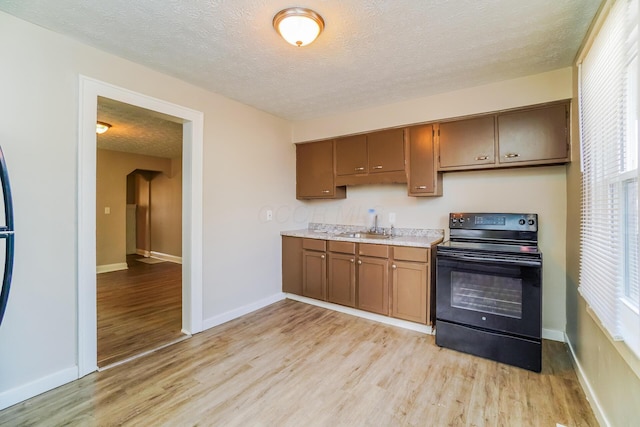 kitchen with black range with electric stovetop, sink, a textured ceiling, and light hardwood / wood-style flooring