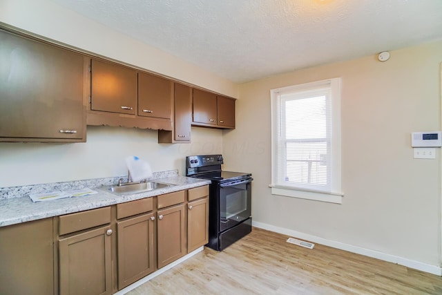 kitchen with sink, black range with electric cooktop, light hardwood / wood-style flooring, and a textured ceiling