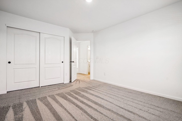 unfurnished bedroom with a closet and light colored carpet