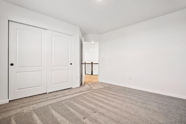 unfurnished bedroom with light colored carpet and a closet