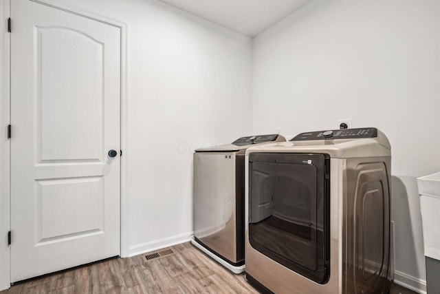 laundry room with independent washer and dryer and hardwood / wood-style flooring