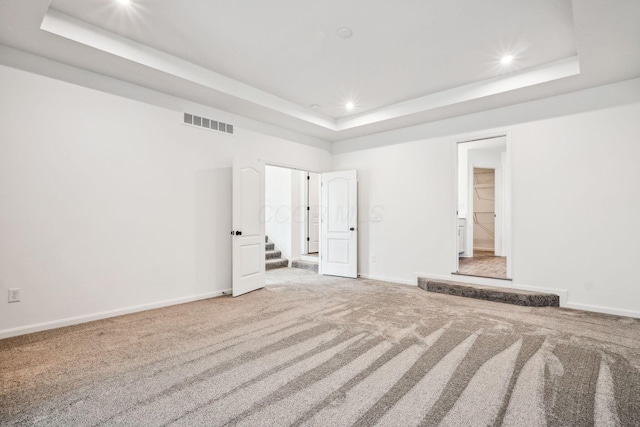 unfurnished bedroom featuring carpet and a raised ceiling