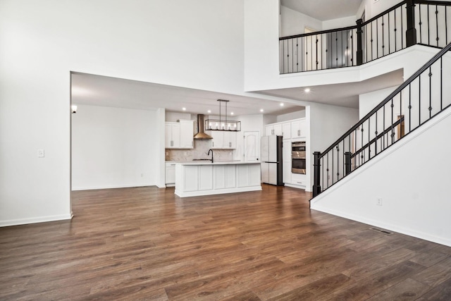 unfurnished living room with sink, a high ceiling, and dark wood-type flooring