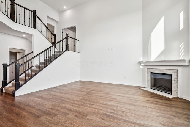 unfurnished living room featuring a fireplace, a high ceiling, and hardwood / wood-style flooring