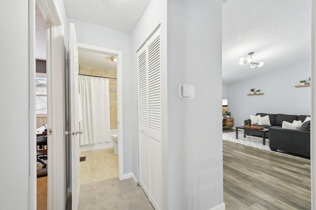 hallway featuring a textured ceiling and an inviting chandelier