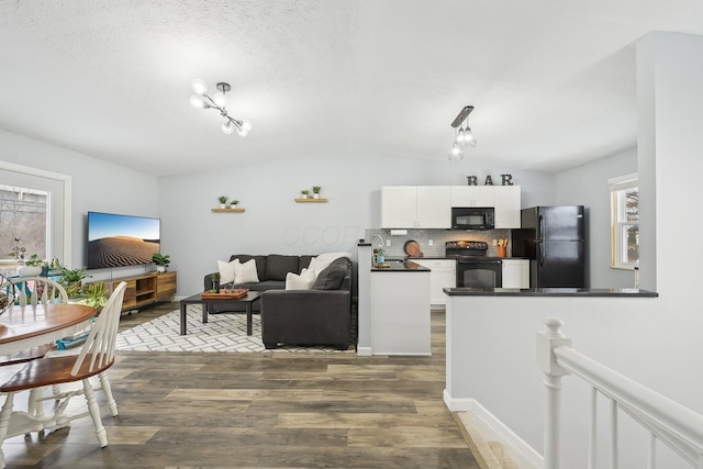 living room featuring lofted ceiling, hardwood / wood-style flooring, a textured ceiling, and an inviting chandelier