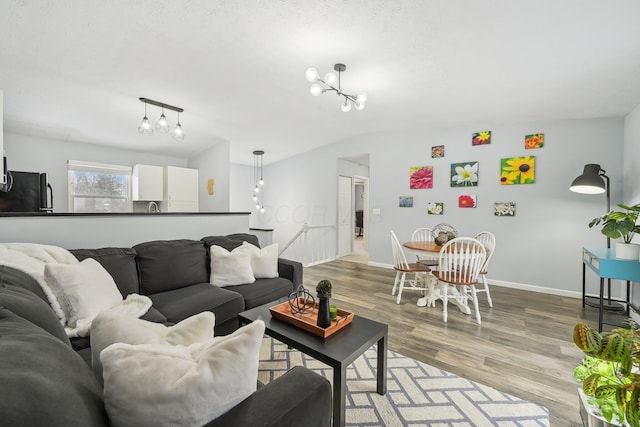 living room featuring wood-type flooring, vaulted ceiling, and a notable chandelier