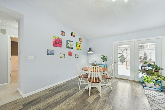 dining area featuring a textured ceiling, vaulted ceiling, and hardwood / wood-style flooring