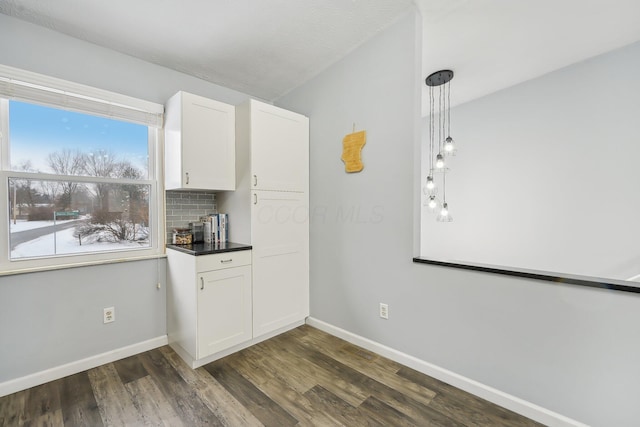 kitchen with decorative light fixtures, decorative backsplash, white cabinetry, and dark hardwood / wood-style floors