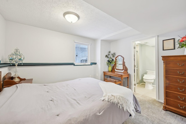 bedroom featuring a textured ceiling, ensuite bathroom, and carpet flooring