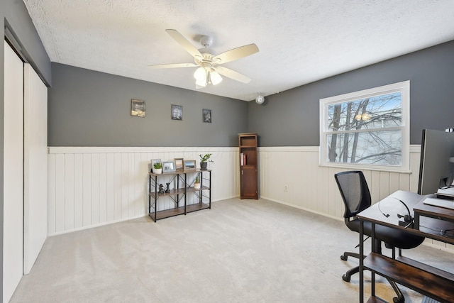 carpeted home office featuring ceiling fan and a textured ceiling