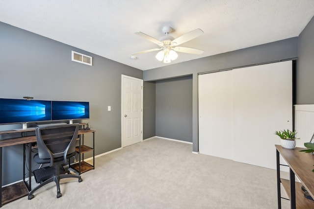 carpeted home office featuring a textured ceiling and ceiling fan