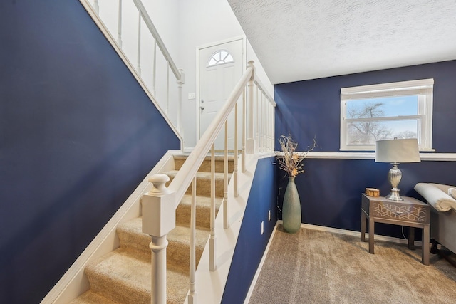 staircase with a textured ceiling and carpet flooring