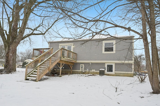 snow covered property with central AC and a wooden deck