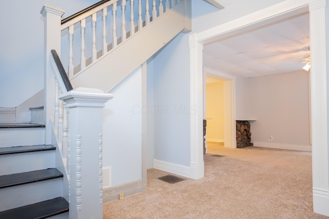 staircase with ceiling fan and carpet