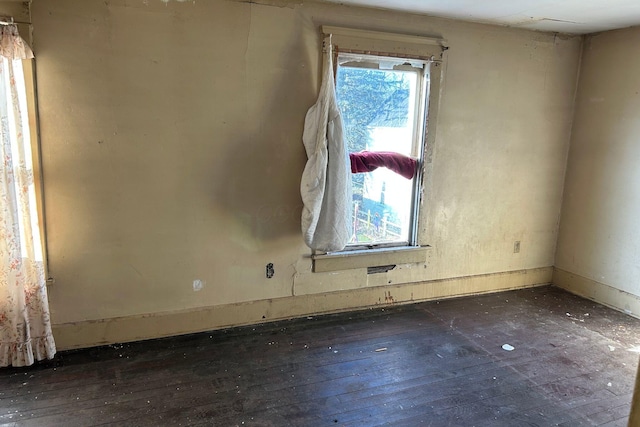 spare room featuring a healthy amount of sunlight and dark hardwood / wood-style flooring