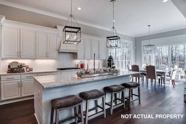 kitchen featuring white cabinets, pendant lighting, a center island, and a breakfast bar