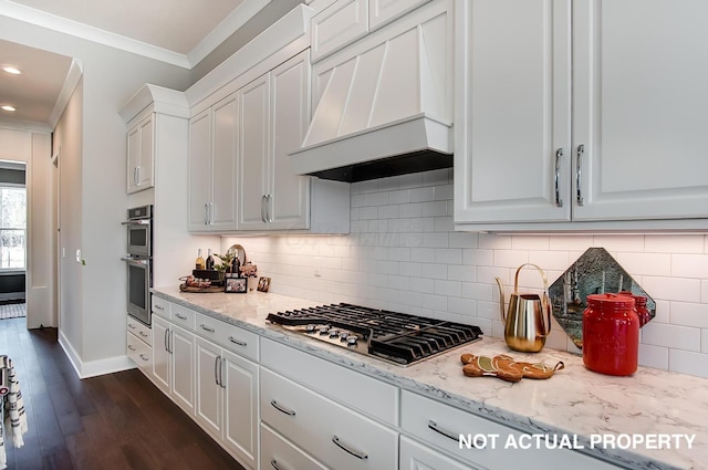 kitchen featuring premium range hood, white cabinets, ornamental molding, and appliances with stainless steel finishes