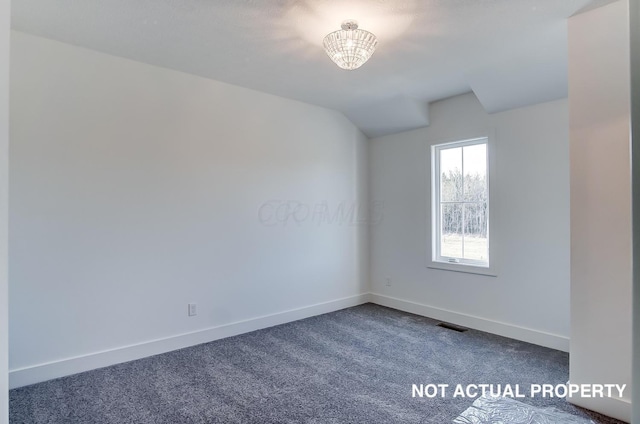 spare room featuring carpet and a chandelier