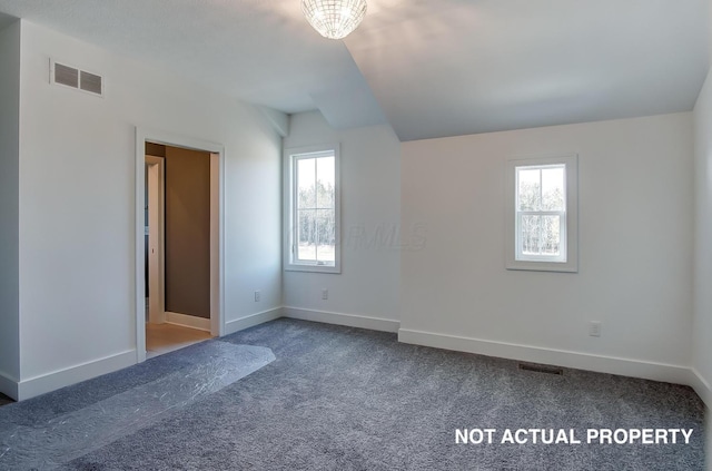 carpeted spare room with a notable chandelier