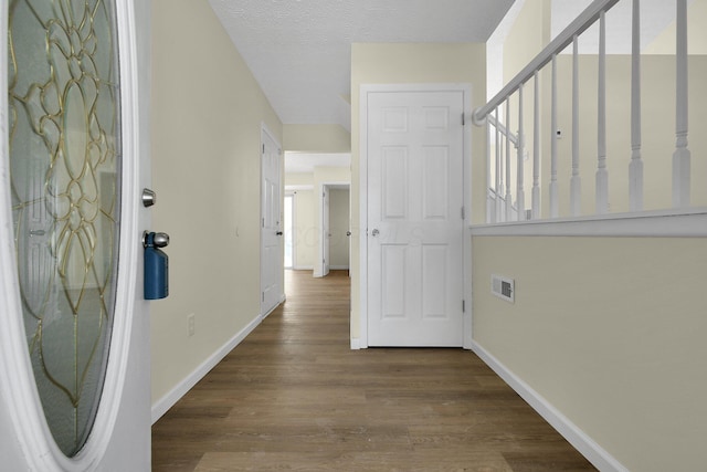 corridor with hardwood / wood-style floors and a textured ceiling