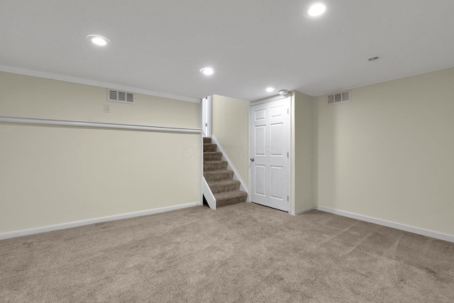 basement featuring light colored carpet and ornamental molding