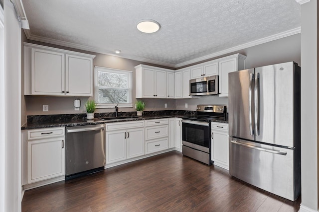 kitchen with appliances with stainless steel finishes, ornamental molding, white cabinetry, and sink