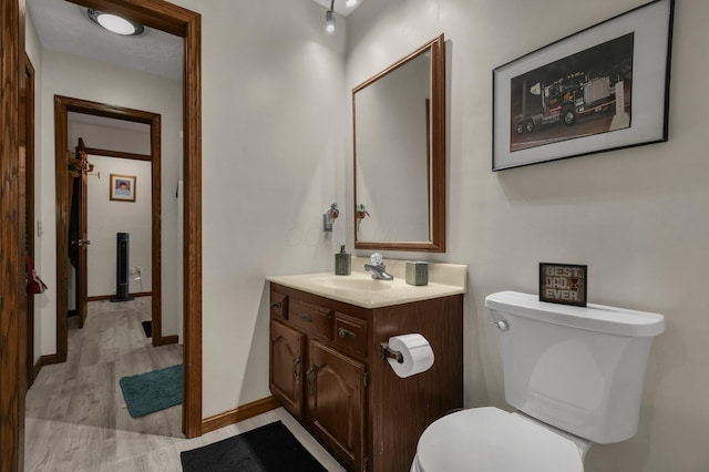 bathroom with wood-type flooring, vanity, and toilet