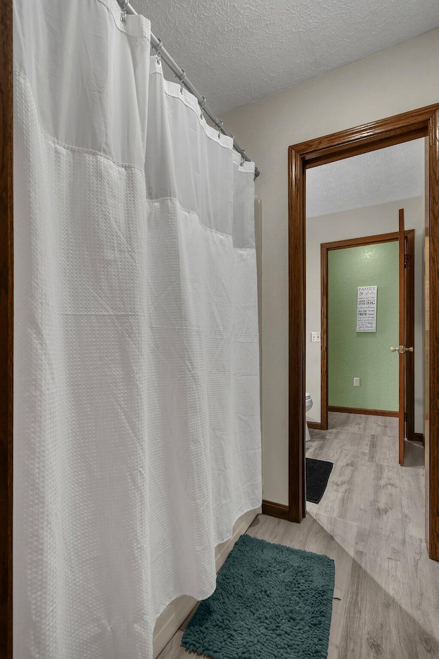 bathroom featuring wood-type flooring and a textured ceiling