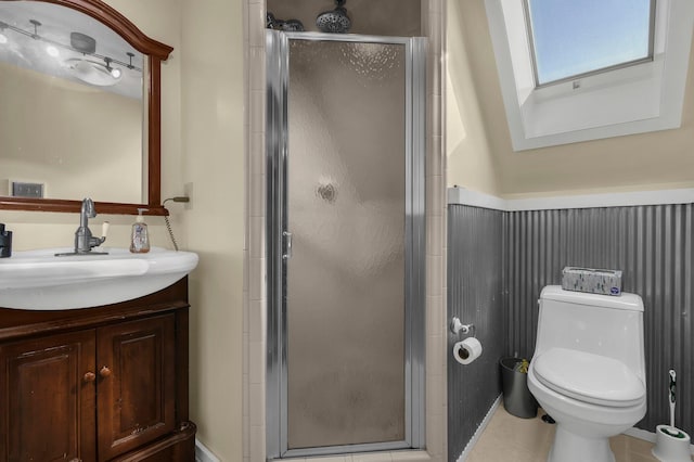 bathroom with vanity, a shower with door, tile patterned floors, a skylight, and toilet