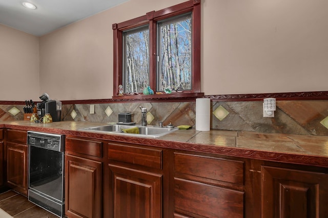 kitchen with dishwasher, backsplash, dark tile patterned floors, and sink