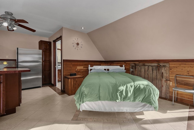 bedroom featuring ceiling fan, wood walls, lofted ceiling, and stainless steel refrigerator