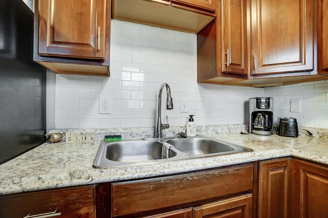 kitchen featuring decorative backsplash, sink, and light stone countertops