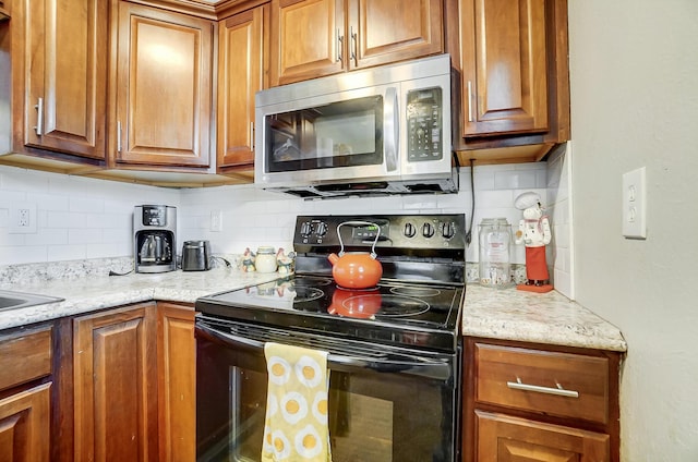 kitchen featuring light stone countertops, black range with electric stovetop, and tasteful backsplash