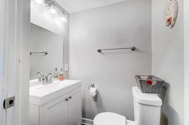 bathroom with vanity, toilet, and a textured ceiling