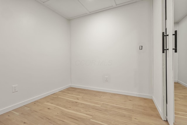 spare room featuring a paneled ceiling and light hardwood / wood-style floors