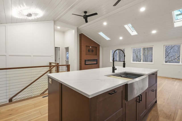 kitchen with ceiling fan, sink, wooden ceiling, light hardwood / wood-style flooring, and a center island with sink