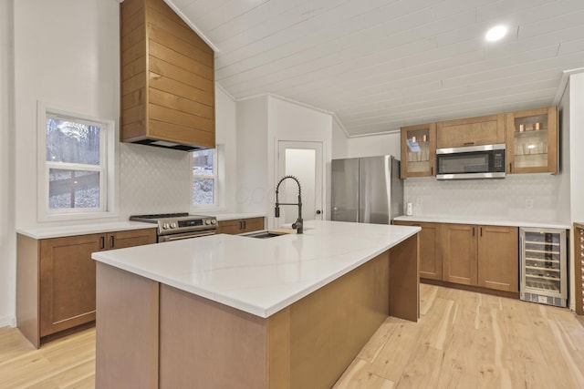 kitchen featuring a kitchen island with sink, stainless steel appliances, beverage cooler, and tasteful backsplash