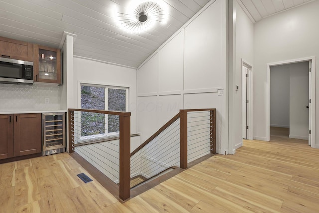 hall featuring light wood-type flooring, high vaulted ceiling, beverage cooler, and wood ceiling