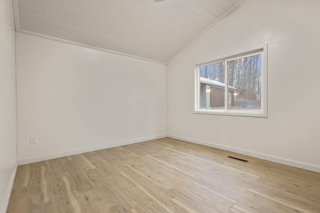 spare room featuring light wood-type flooring and vaulted ceiling