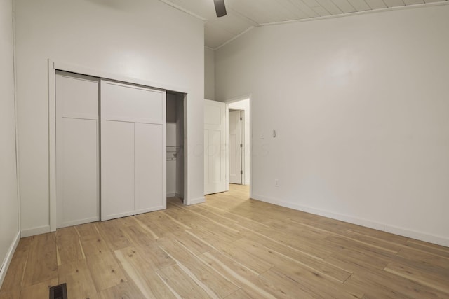 unfurnished bedroom with a closet, ceiling fan, light hardwood / wood-style flooring, and high vaulted ceiling