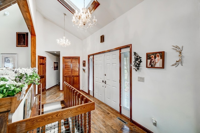 foyer entrance with a chandelier, light wood-type flooring, high vaulted ceiling, and a healthy amount of sunlight