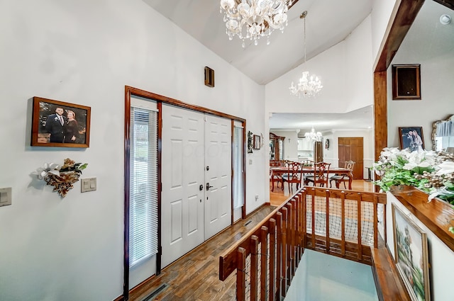 entryway featuring wood-type flooring, high vaulted ceiling, and an inviting chandelier