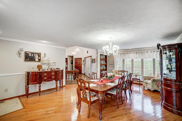 dining room with ornamental molding, a chandelier, a textured ceiling, and light hardwood / wood-style floors