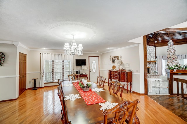 dining area with a textured ceiling, light wood-type flooring, crown molding, and a chandelier