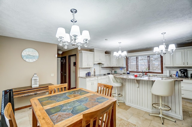 dining space featuring light tile patterned floors, a chandelier, and a textured ceiling