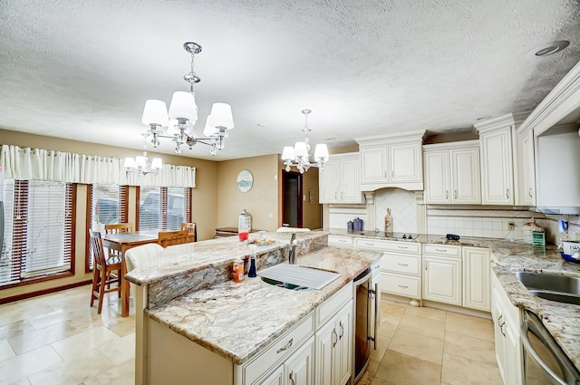 kitchen featuring backsplash, a kitchen island with sink, hanging light fixtures, stainless steel dishwasher, and a notable chandelier