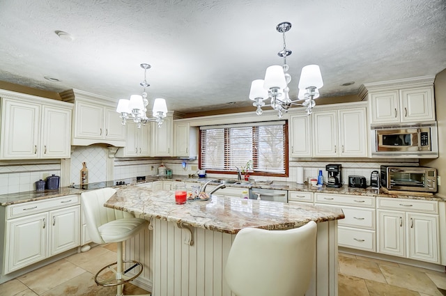 kitchen featuring light stone countertops, appliances with stainless steel finishes, pendant lighting, a notable chandelier, and a center island