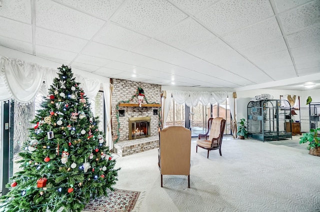 carpeted living room with a paneled ceiling and a brick fireplace