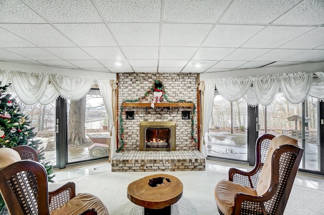 living room with tile patterned flooring, a paneled ceiling, and a fireplace